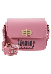 Rosa syntetisk læderhåndtaske med et guldfarvet spænde, der har et farverigt logodesign og en aftagelig rem med branding. Kompakt rektangulært design.