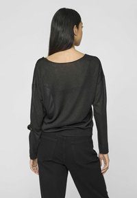 Mustat neulottu villapaita, jossa on löysä istuvuus ja avara kaula-aukko. Paidan pitkät hihat ja ribbireunus. Yhdistetty mustiin housuihin.