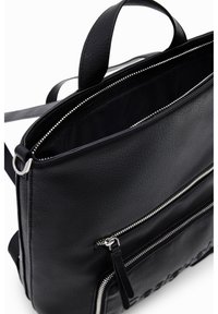 Czarny skórzany plecak o fakturowanej powierzchni, z srebrnymi zamkami błyskawicznymi, dwoma przednimi kieszeniami na zamek oraz górnym uchwytem do noszenia. Wnętrze wyłożone jest materiałem.