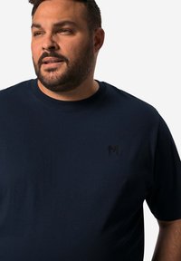 Granatowa koszulka z krótkim rękawem wykonana z miękkiego materiału. Posiada okrągły dekolt oraz subtelne czarne logo na piersi. Prosty, jednolity wzór.