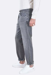 Jeans in denim grigio con una vestibilità comoda, orli risvoltati, design a cinque tasche e un leggero sbiadimento. Abbinati a sneaker bianche.