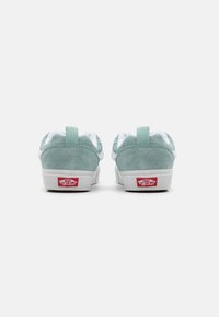 Baskets en daim vert menthe avec des accents blancs, dotées d'une languette de tirage, d'un col rembourré et d'un logo rouge au talon. Design épuré et simple.