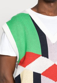 Chaleco de punto con un patrón geométrico en verde, rojo, negro, crema y rosa; escote en forma de v y tirantes anchos.