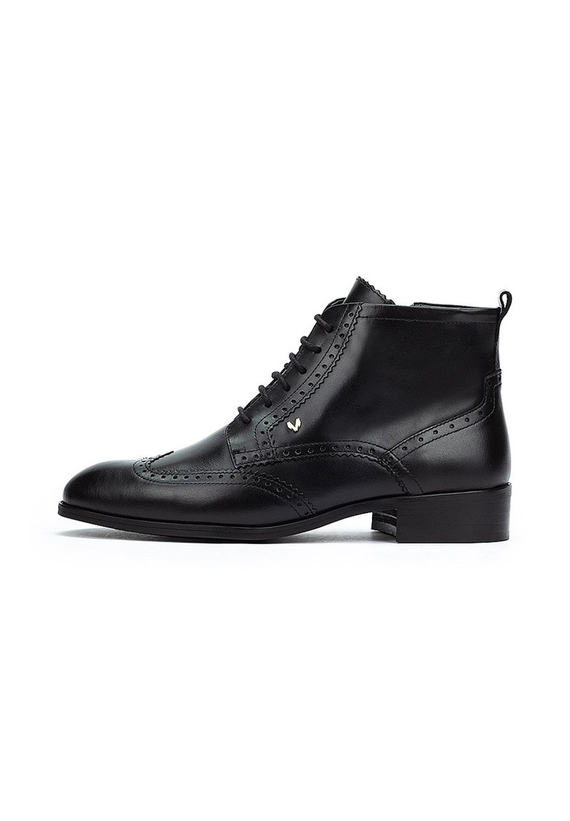 Botín de cuero negro hasta el tobillo con punta afilada, detalles decorativos de brogue, parte frontal con cordones y un pequeño tacón. Textura suave con acento dorado.