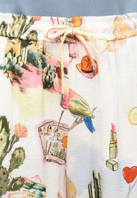 Παντελόνια με κορδόνι και πολύχρωμα σχέδια με κάκτους, πουλιά, τράπουλα, κραγιόν και μπαλόνια σε σχήμα καρδιάς σε λευκό φόντο.