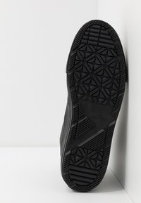 Svart gummisåle til sneakers med et geometrisk mønster og preget merkevarelogo. Designet er flatt med teksturerte detaljer.