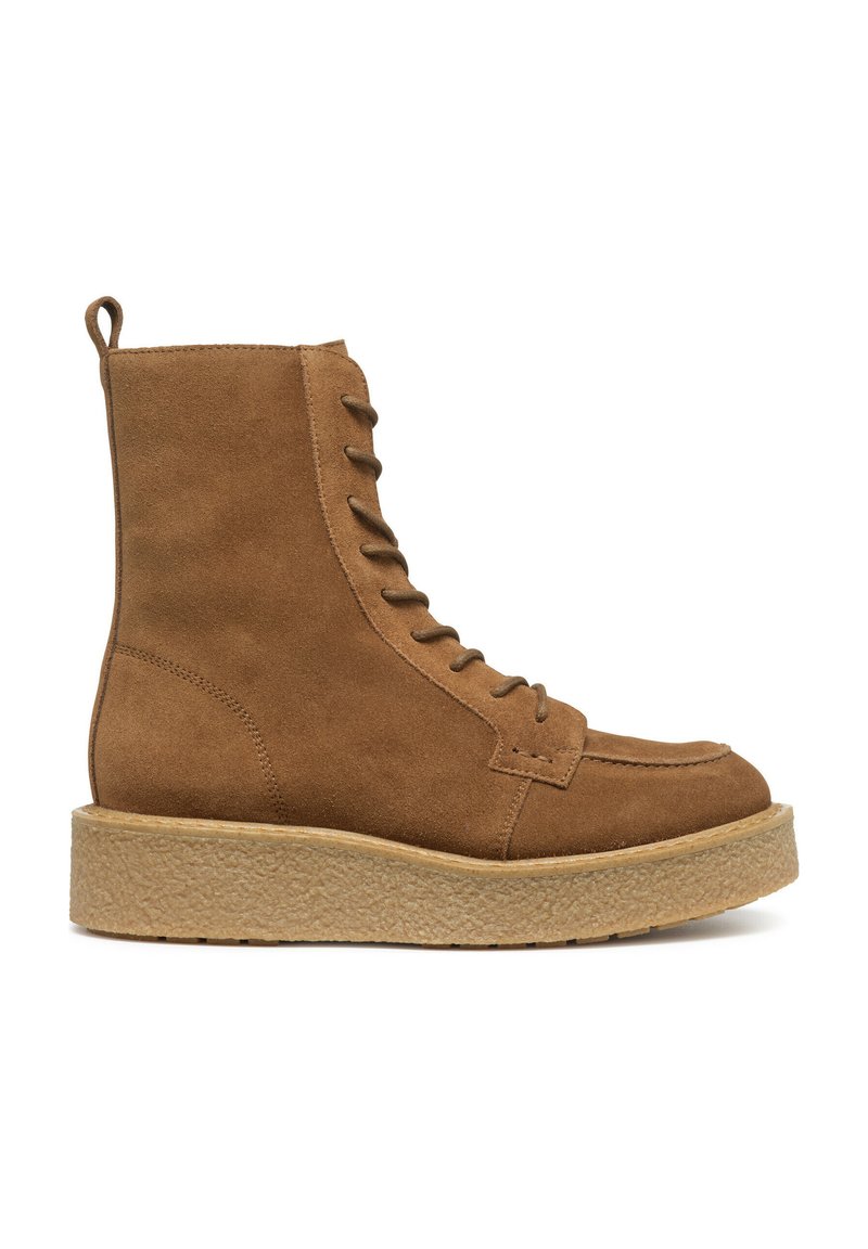 Stivale alla caviglia in suede marrone con punta tonda, dotato di lacci frontalmente, maniglia per indossarlo facilmente e suola texturizzata e chunky per un'altezza aggiuntiva.