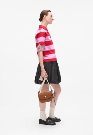 Rood en roze gestreepte polo, zwarte geplooide rok, bruine leren handtas, crèmekleurige sokken en zwarte loafers met studs.