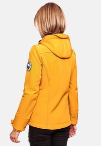 Yellow hooded jacket with a fitted design, textured fabric, and a round patch on the left sleeve. Visible stitching and cuffs detail.