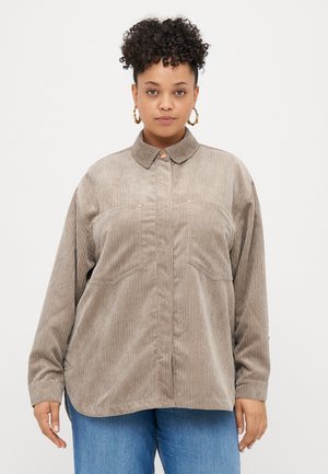 Lysbrun fløjlsskjorte med klassisk krave, to forlommer og en afslappet pasform. Kobberknapper tilføjer subtile detaljer.