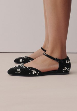 Black velvet flat shoes with an ankle strap, featuring an embellished design of rhinestones and floral accents on the toes.