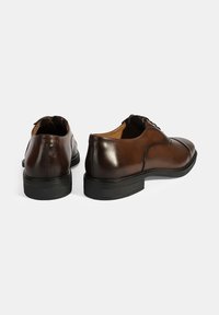 Bruine leren veterschoenen met een gladde afwerking, ronde neus en zwarte rubberen zool met een gestructureerd patroon.