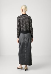 Μαύρο και άσπρο πουλόβερ με σχέδιο, με μονόχρωμο μαύρο τελείωμα, συνδυασμένο με μακριά γκρι τζιν φούστα και σανδάλια με τακούνι σε σχέδιο φίδι.