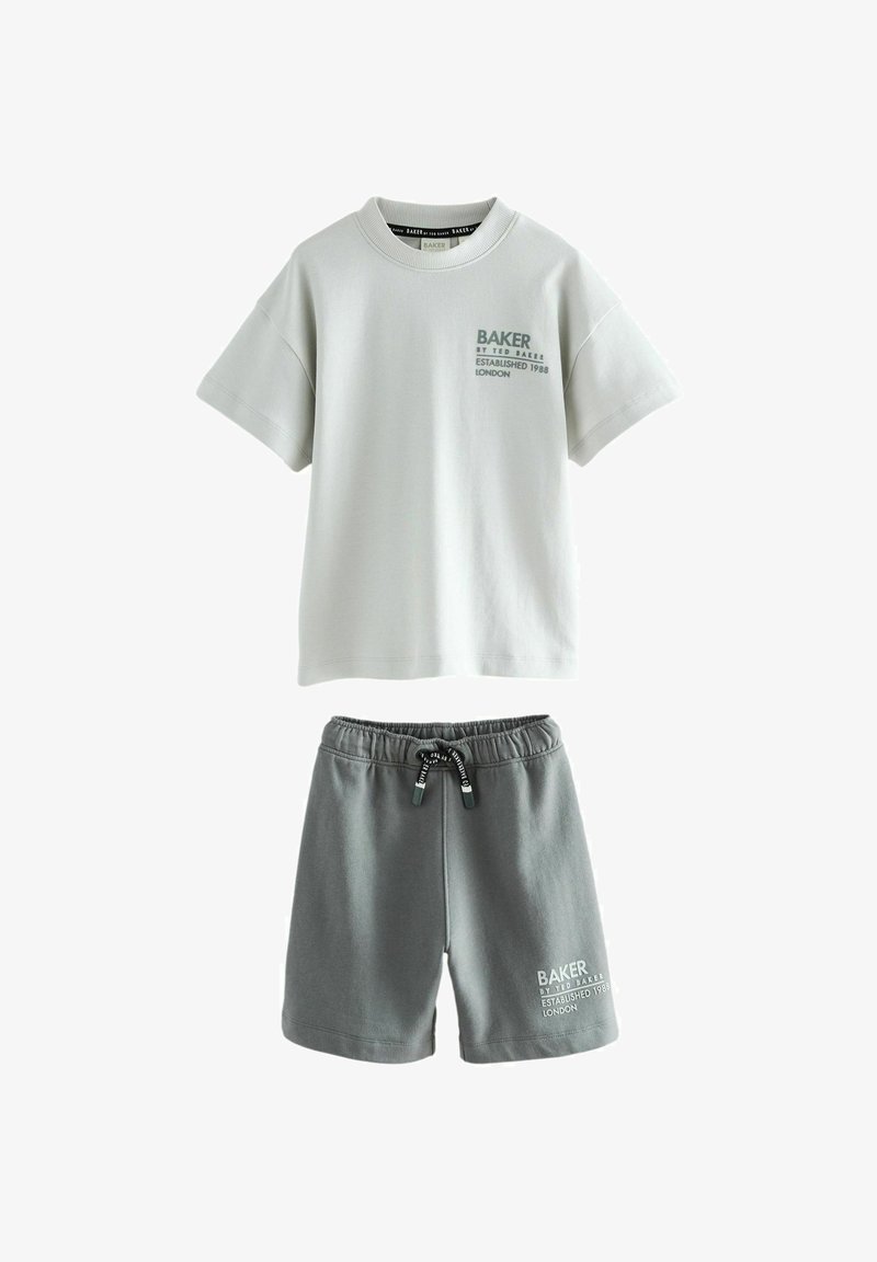 Šviesiai pilkas medvilninis marškinėliai su trumpomis rankovėmis ir žaliai spausdintu tekstu; derinami su tamsiai pilkais medvilniniais šortais, turinčiais virvutę ir logotipo detalę.