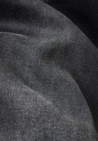 Tejido de mezclilla oscura con una textura suave, un ligero brillo y un patrón de sarga visible. El material presenta variaciones en la profundidad, creando un interés visual.