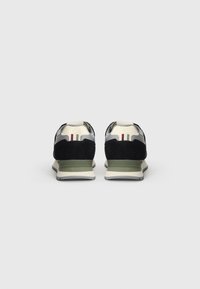 Schwarze und graue Sneakers mit einer strukturierten Wildleder-Oberfläche, grünen Akzenten und einer weißen Sohle. Sie verfügen über einen gepolsterten Schaft und ein Nylon-Mesh-Material.