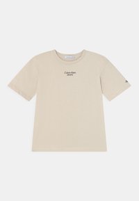 Béžové bavlněné tričko s kulatým výstřihem, krátkými rukávy a jemným černým potiskem loga "Calvin Klein Jeans" na přední straně.