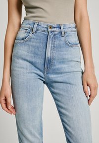 Ljusblå högmidjade jeans med en figurnära passform, som har fem fickor, synlig sömnad och metallknappstängning.