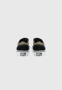 Baskets en suede noir et imprimé léopard avec une semelle en caoutchouc blanc, dotées d'une languette au talon et du logo Vans à l'arrière.
