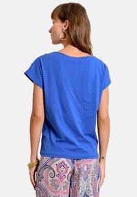 Camiseta de algodón azul con mangas cortas, cuello redondo y un ajuste relajado, combinada con pantalones sueltos de patrón.