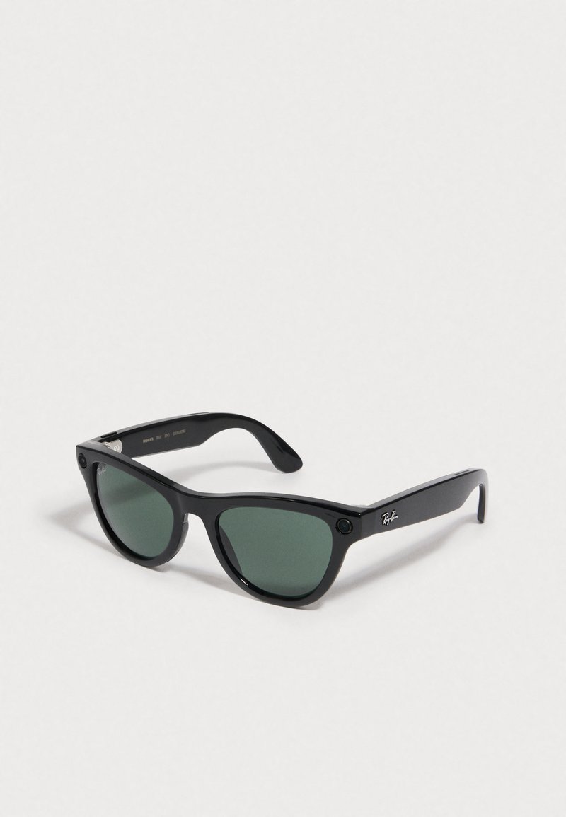 Gafas de sol de plástico negro con lentes verdes, forma de ojo de gato, acentos metálicos y logotipo de Ray-Ban en una de las varillas.