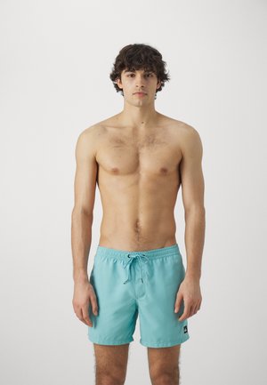 Bañador turquesa con cintura elástica y cordón. Diseño sencillo, tejido ligero y pequeño logo en el lateral.