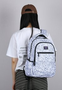 Zaino con un motivo a foglie bianche e blu, dotato di cerniere nere e spallacci imbottiti. Realizzato in tessuto resistente con una finitura texturizzata.