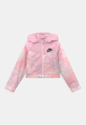 Veste coupe-vent Nike rose, dotée d'une capuche, d'une fermeture éclair à l'avant et d'un motif abstrait aquarelle avec un logo noir sur la poitrine.
