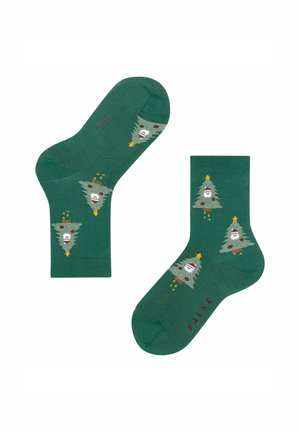 Grüne Socken mit einem gestrickten Design, das cartoonhafte Weihnachtsbäume und weiße Gesichter zeigt. Enthält rote Akzente und Details mit goldenen Sternen.