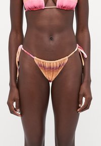 Ensemble de bikini tie-dye avec un dégradé de couleurs rose et orange. Le bas a un design froncé avec des liens sur les côtés. Texture de tissu douce.