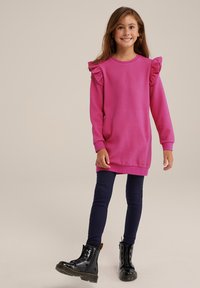Fuchsia long-sleeve dress with textured pattern and ruffle accents at shoulders, paired with navy leggings and black ankle boots.
