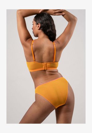 Oranssi rintaliivit ja niihin sopivat alushousut, jotka on valmistettu pehmeästä ja sileästä kankaasta. Niissä on säädettävät hihnat ja kontrastiväriset saumat reunojen ympäri.