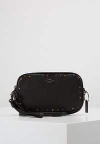 Borsa a tracolla Coach in pelle nera con borchie colorate lungo il bordo, caratterizzata da un logo frontale, chiusura con cerniera e tracolla removibile.