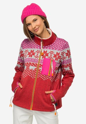 Giacca in pile rossa con un design a fantasia caratterizzato da elementi bianchi e rosa, una tasca con zip rosa e zip e lacci di contrasto arancioni.