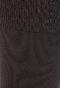 Tessuto di maglia nera con una texture a costine. La parte superiore presenta un motivo a costine più largo, che si trasforma in un'abitazione più fine nella parte inferiore.