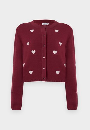 Burgunderfarbener, kurzer Cardigan mit langen Ärmeln und weißen, gestickten Herzen, die auf der Vorderseite verteilt sind. Knöpfe in der Mitte und gerippter Saum.