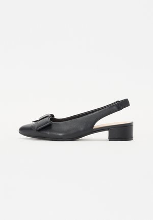 Sorte skinnslyngebåndssko med rund tå, liten blokkhelt, og en dekorativ sløyfe foran. Glatt tekstur og minimalistisk design.