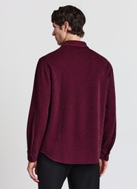 Bordeauxrotes Langarmshirt mit dezentem Schimmer, lässigem Schnitt und mit Knöpfen versehenen Manschetten. Verfügt über einen klassischen Kragen und einen leicht geschwungenen Saum.
