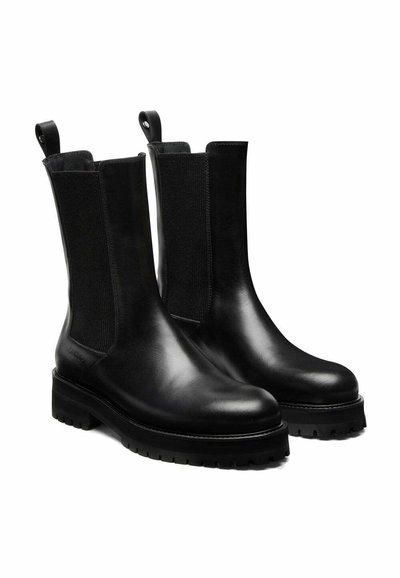 Des bottines noires en cuir avec des panneaux élastiques sur les côtés, des semelles robustes et des tirettes pour un enfilage facile. Texture lisse et design épuré.