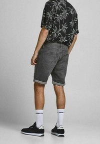 Gray denim shorts with rolled hems, paired with a black tropical-print shirt. Finished with black sneakers and white crew socks.