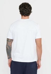 T-shirt bianca a maniche corte con scollo a girocollo, realizzata in tessuto morbido, con vestibilità rilassata e cuciture piatte.