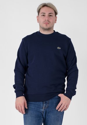 Navy blue sweatshirt made of cotton, featuring a ribbed crew neck and cuffs, with a small embroidered logo on the chest.