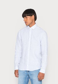 Camicia di cotone a righe blu e bianche con maniche lunghe, colletto alla francese e vestibilità slim. Presenta una tasca frontale e chiusure a bottoni.