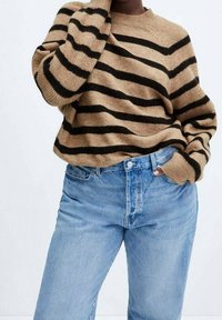 Pull rayé marron et noir avec un col rond, coupe ample, poignets côtelés, assorti à un jean en denim taille haute bleu clair.