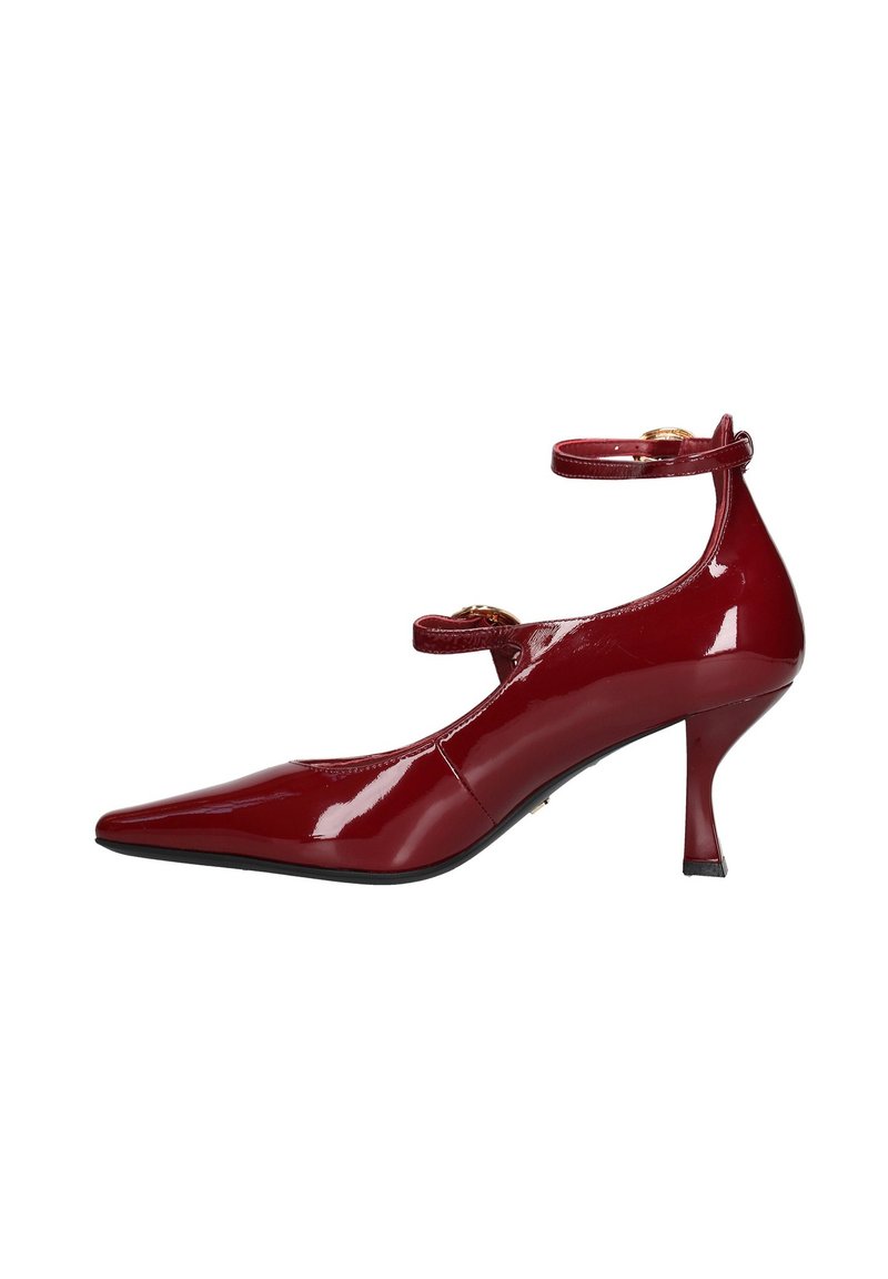 Scarpa con tacco alto in pelle verniciata rossa, punta affusolata, cinturini alla caviglia e tacco sottile. Presenta dettagli in hardware tono oro.