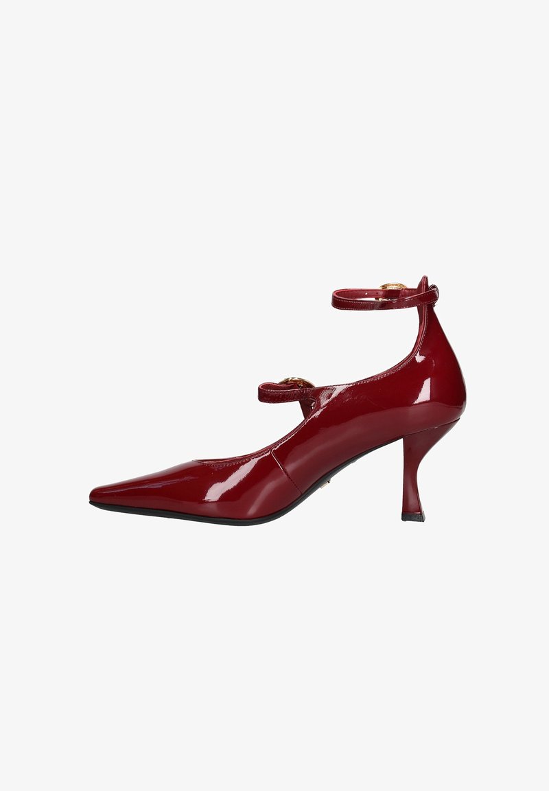 Scarpa con tacco alto in pelle verniciata rossa, punta affusolata, cinturini alla caviglia e tacco sottile. Presenta dettagli in hardware tono oro.