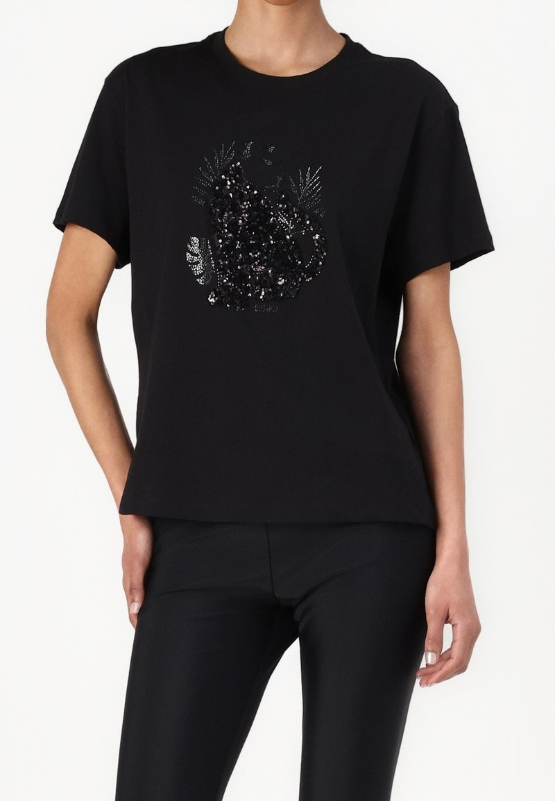Black cotton t-shirt with short sleeves, featuring a sequined decorative design of foliage and an animal. Casual, relaxed fit.
