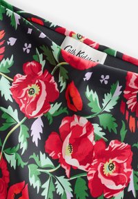 Material floral cu maci roșii mari și frunze verzi pe fundal negru. Include o etichetă Cath Kidston. Textură netedă.