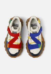 Bunte Sneakers mit einem Design aus verschiedenen Materialien. Sie verfügen über rote, blaue und grüne Riemen auf einem cremefarbenen Obermaterial und haben eine strukturierte braune Sohle.
