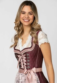 Burgunderrote Dirndlbluse mit einer Lace weißen Bluse, die einen V-Ausschnitt, silberne Beschläge, kunstvolle Muster und ein Taillenband aus Satin aufweist.